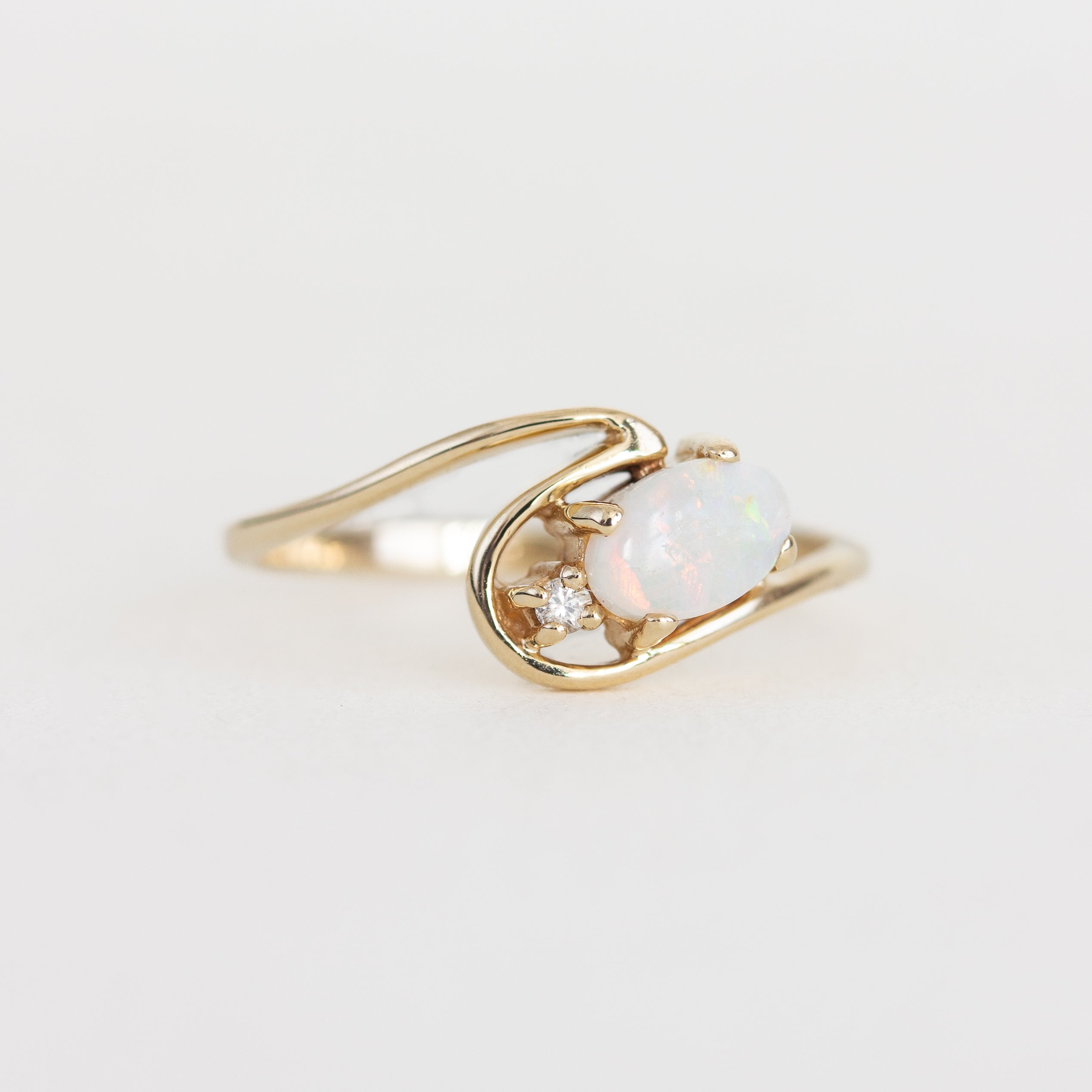 Gold ring with an opal stone on a light gray background