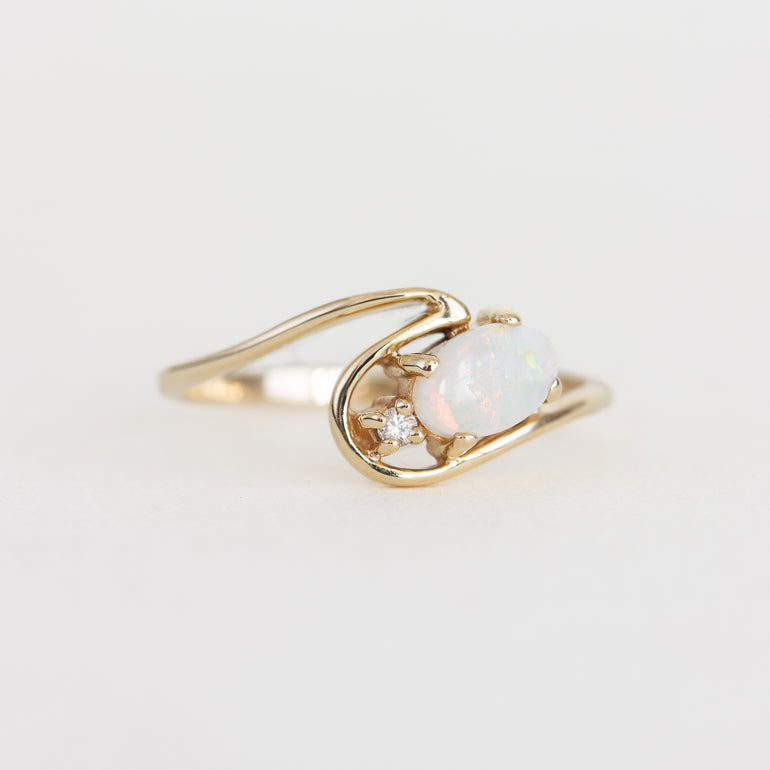 Gold ring with an opal stone on a light gray background