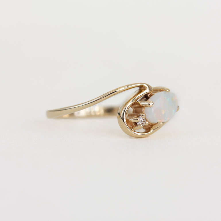 Gold ring with an opal stone on a light gray background