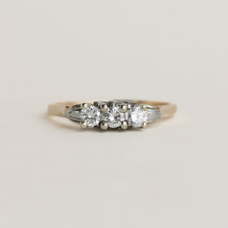 Three-stone diamond ring on a light gray background