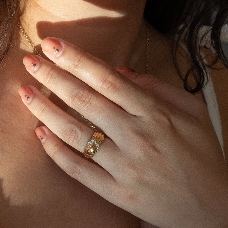 Close-up of a woman wearing a gold ring on her finger, with sunlight casting shadows.