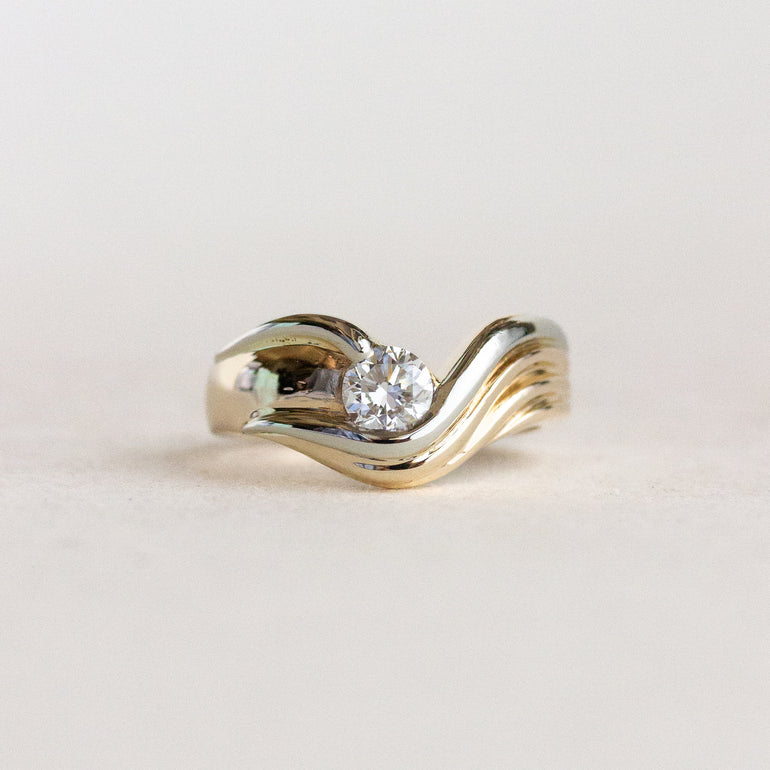 Gold ring with a diamond on a light gray background