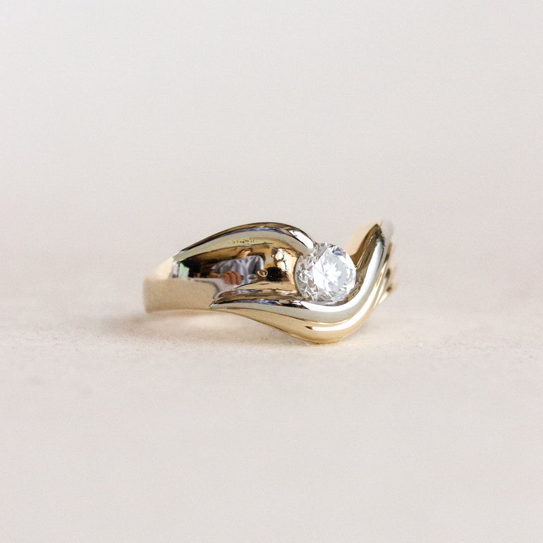 Gold ring with a diamond on a light beige background