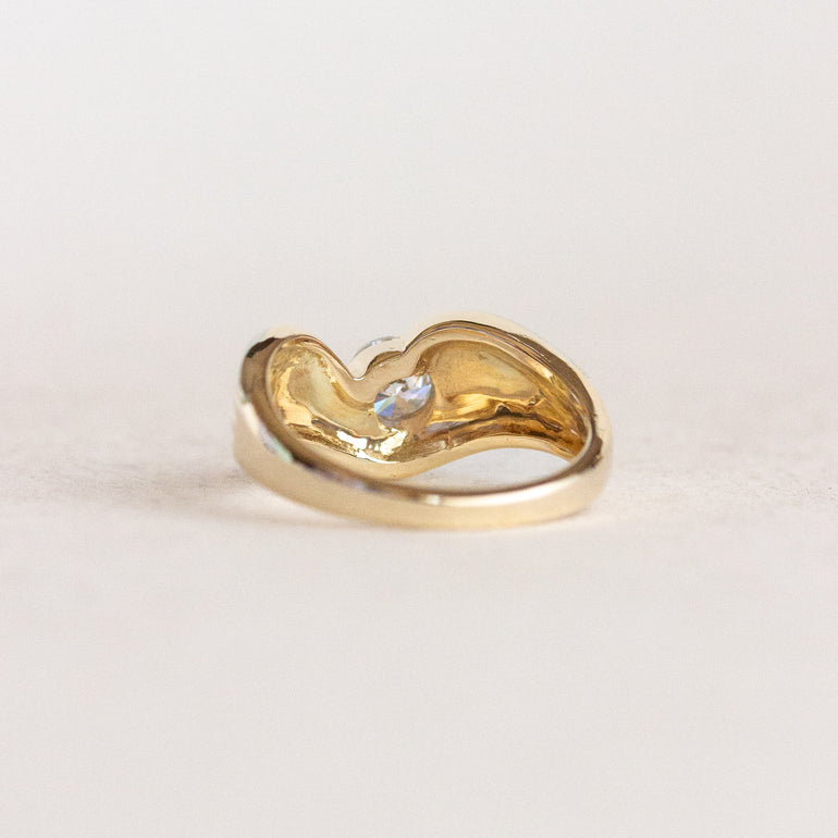 Gold ring with a heart design on a light beige background