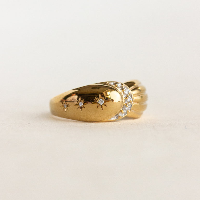 Gold ring with star designs on a light beige background
