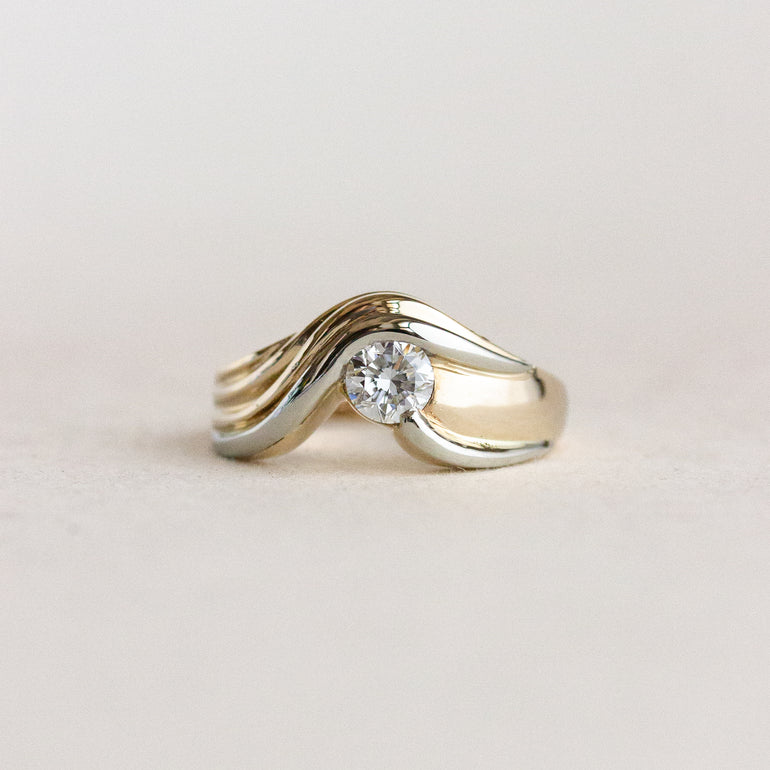Two-tone ring with a diamond on a light beige background