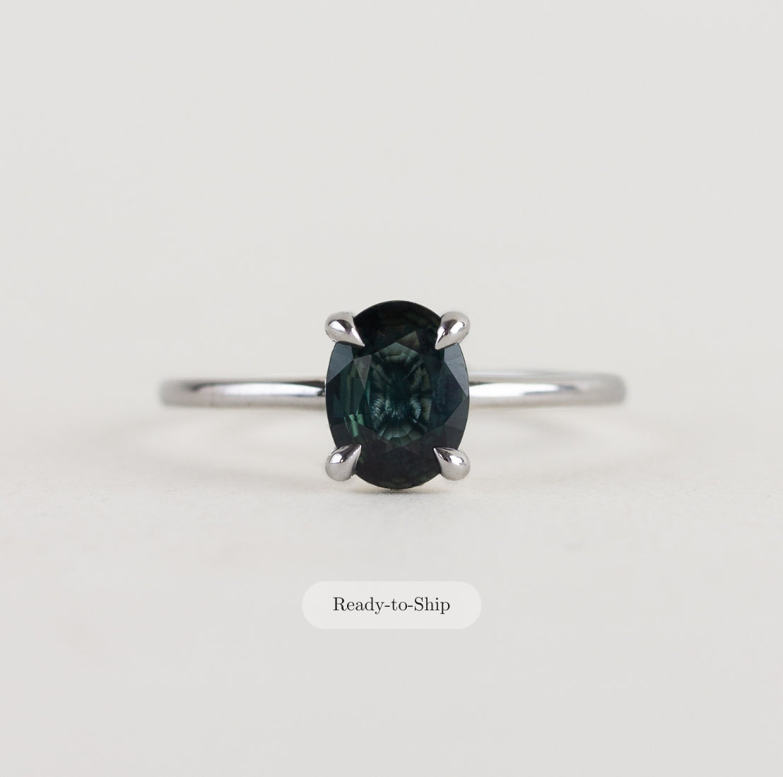 14K white gold ring with a moody dark teal sapphire