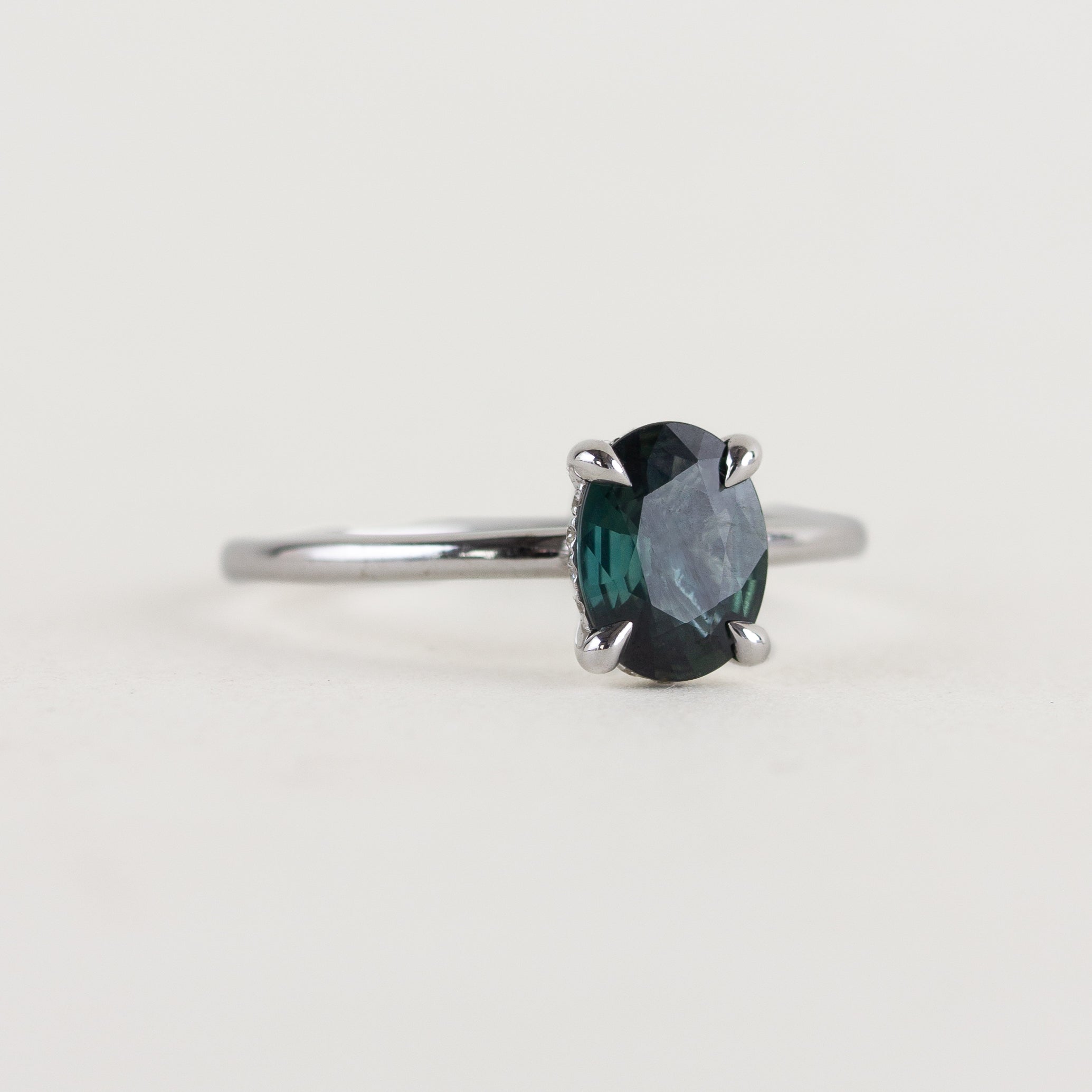14K white gold ring with a moody dark teal sapphire