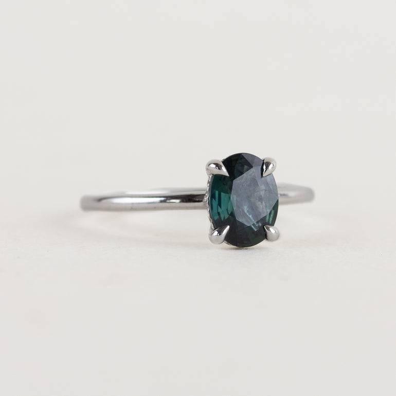 14K white gold ring with a moody dark teal sapphire