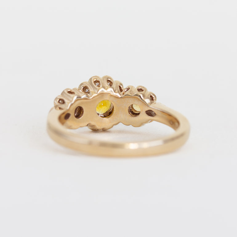 Gold ring with a yellow gemstone on a light gray background