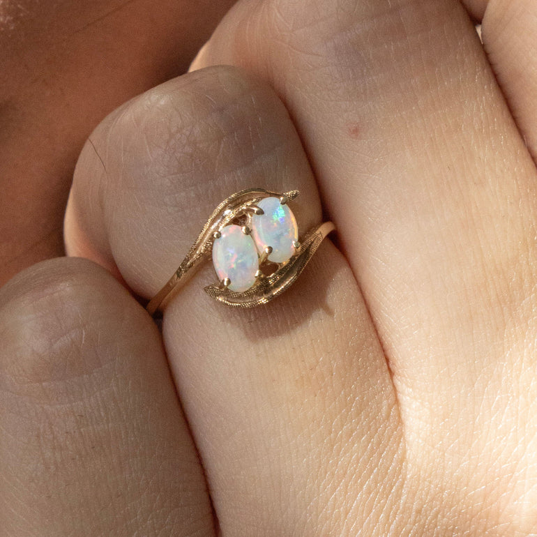 Close-up of a hand wearing a gold ring with a gemstone against a dark background