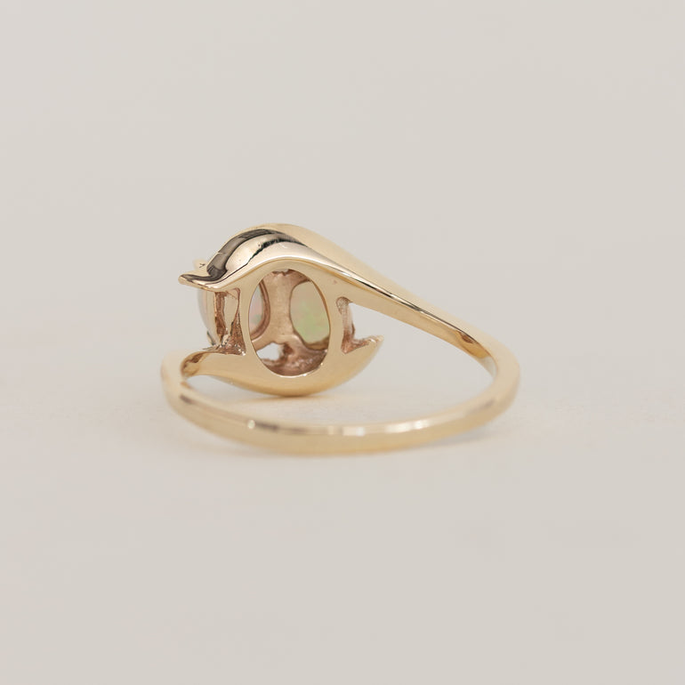 Gold ring with a green gemstone on a light gray background