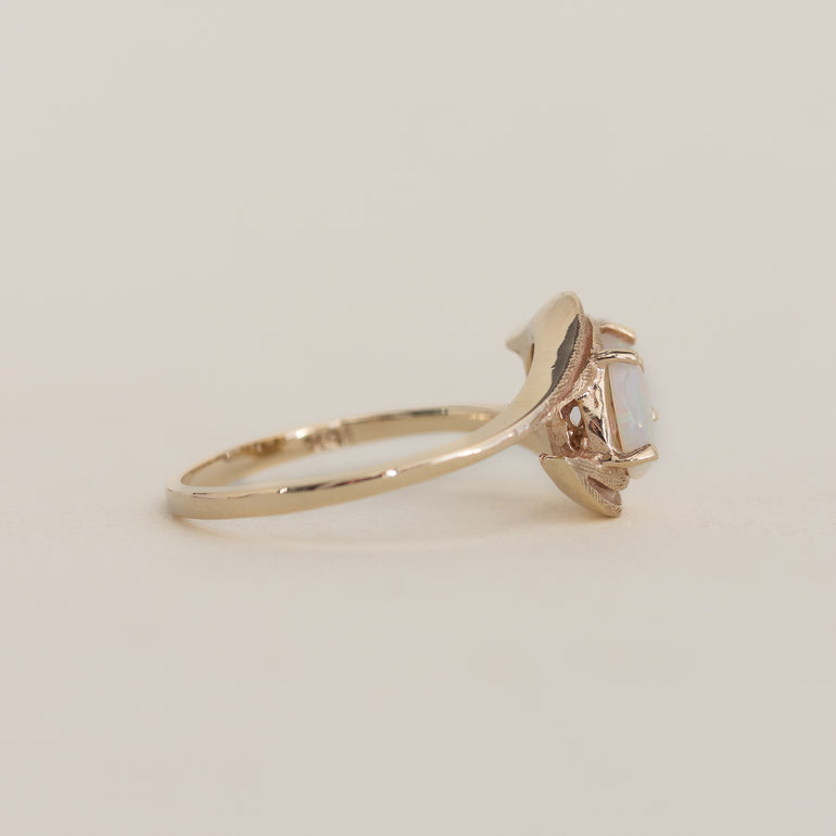 Gold ring with a central gemstone on a beige background