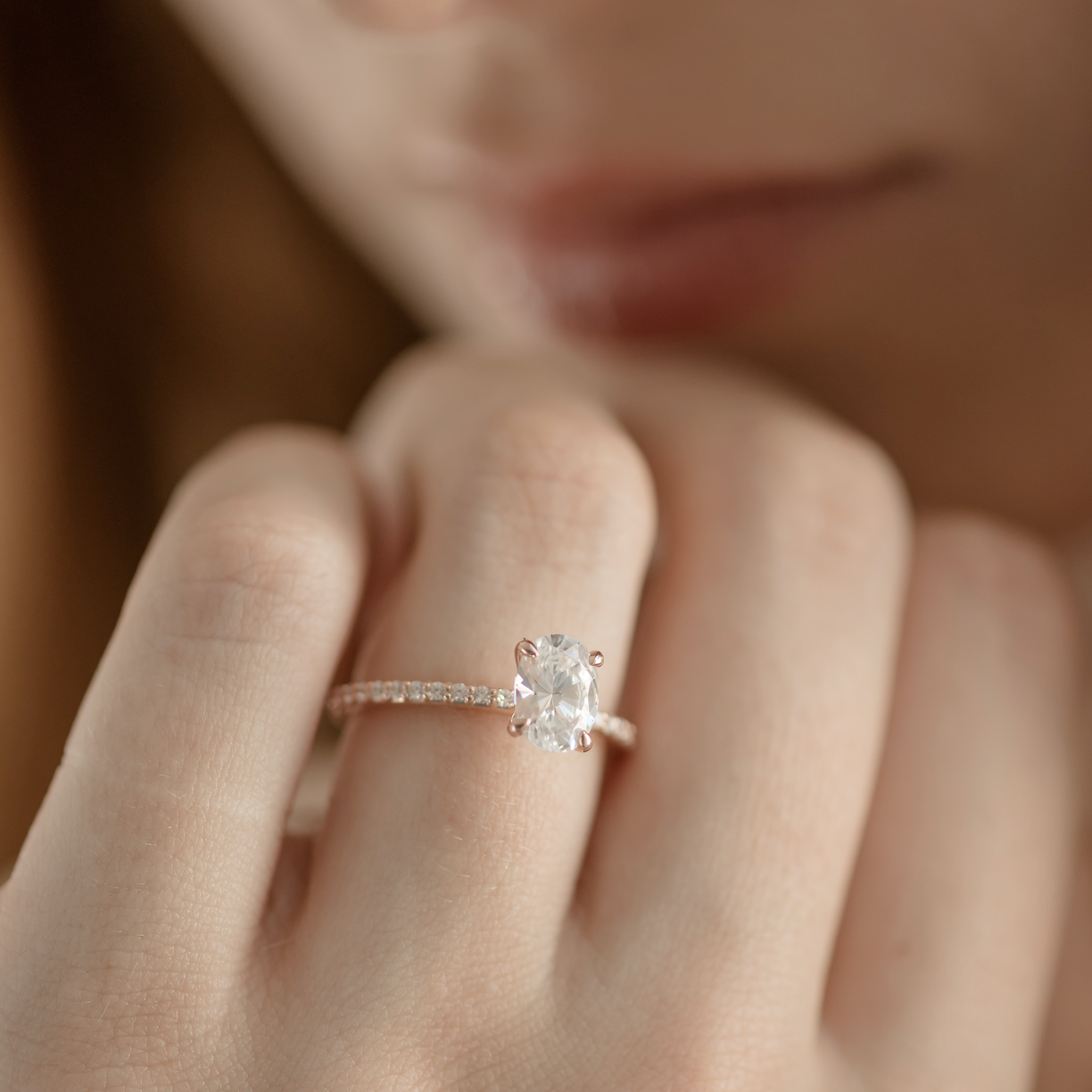 Close-up of a hand wearing a diamond ring with a blurred background