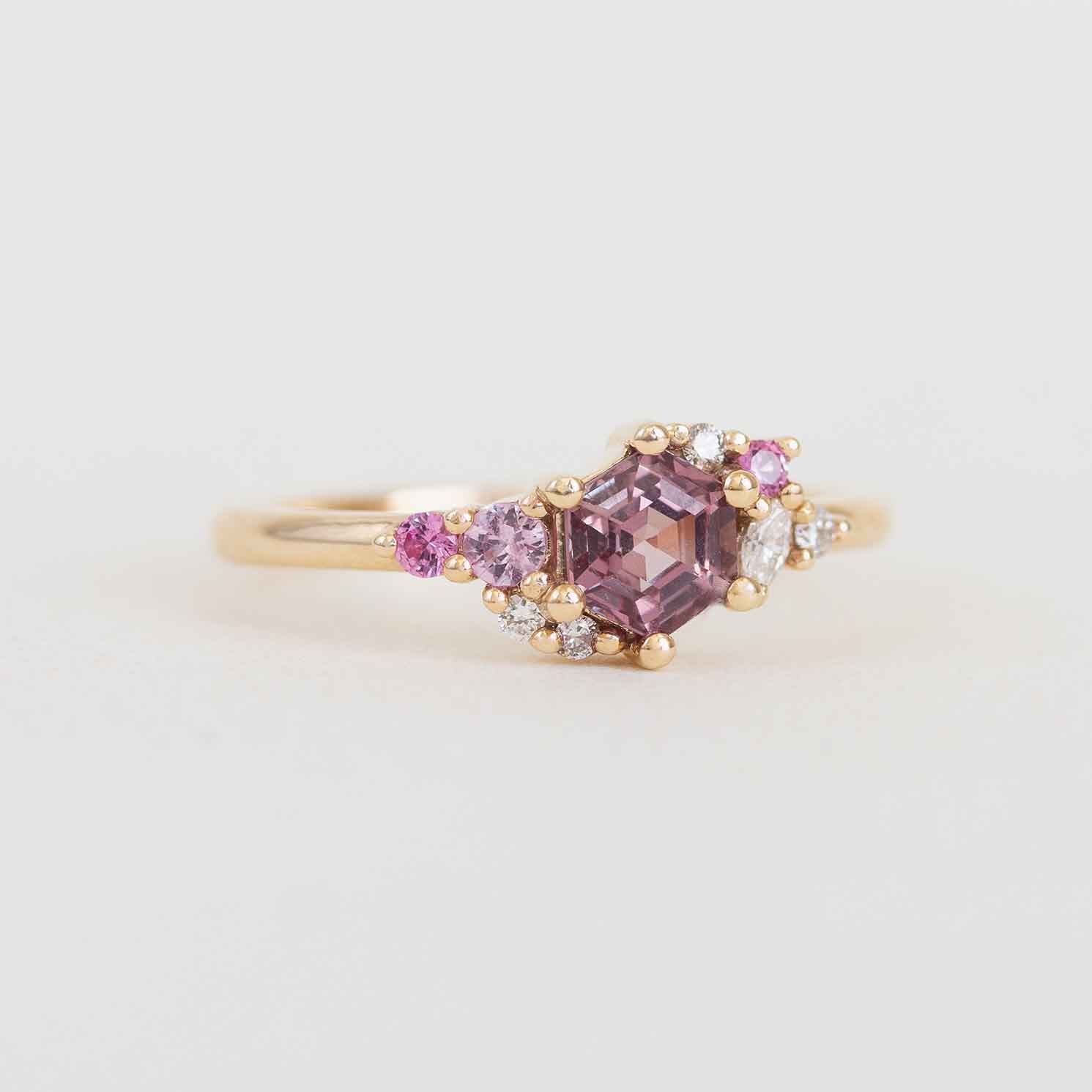 Gold ring with pink gemstones on a light gray background