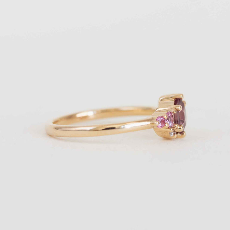 Gold ring with pink gemstones on a light gray background