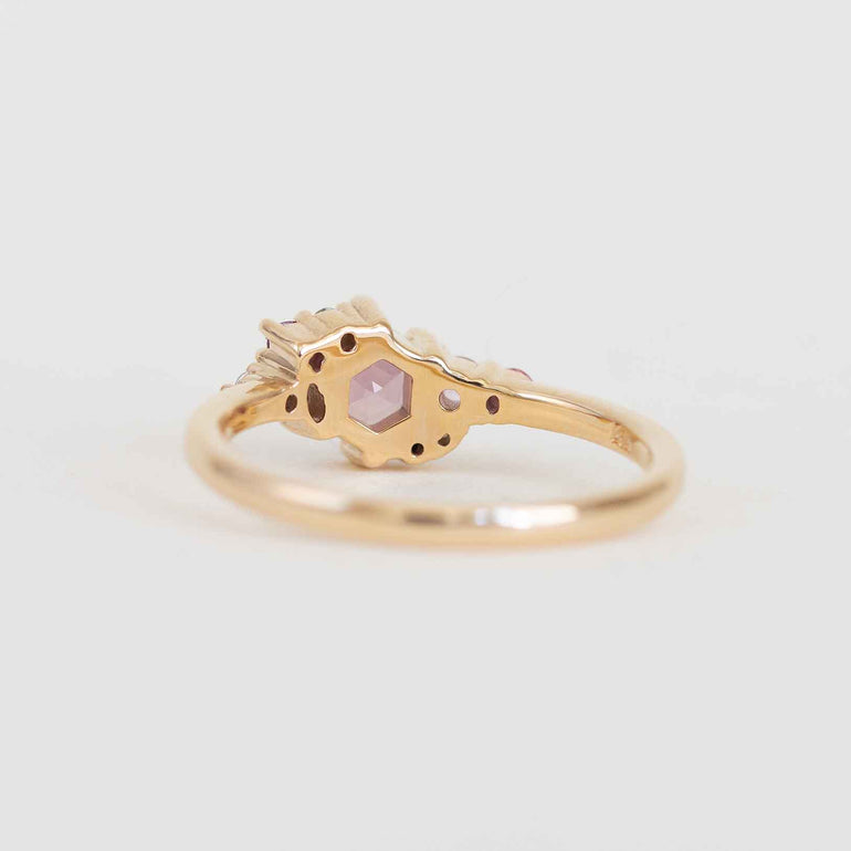 Gold ring with a pink gemstone on a light gray background