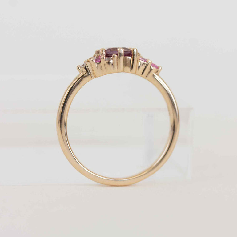 Gold ring with pink gemstones on a light gray background