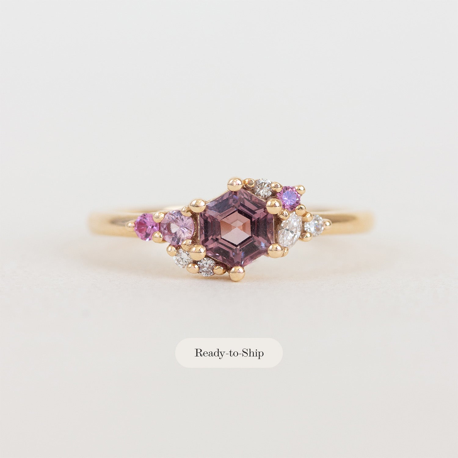 Gold ring with purple gemstone on a light gray background