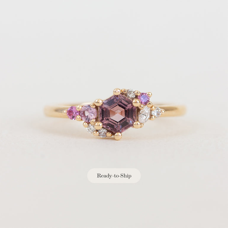 Gold ring with purple gemstone on a light gray background