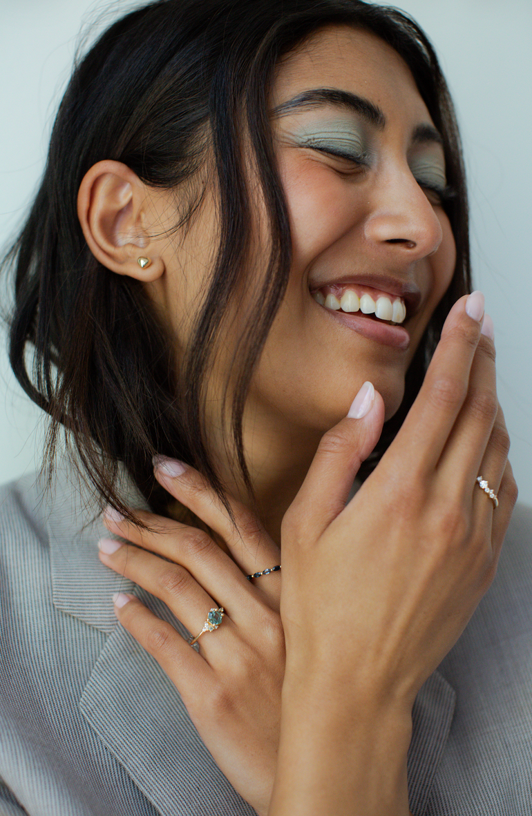 Woman wearing earrings and rings with a neutral background