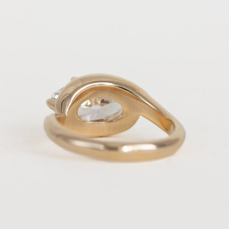 Gold ring with a clear gemstone on a light gray background