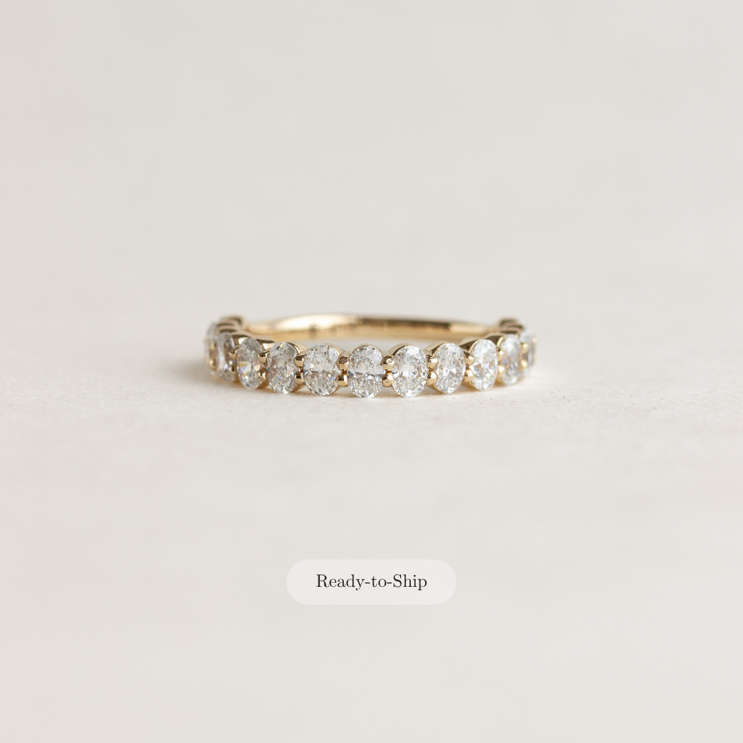 A yellow gold eternity ring with a row of round-cut diamonds, shown on a light beige background with a 'Ready-to-Ship' label below it.