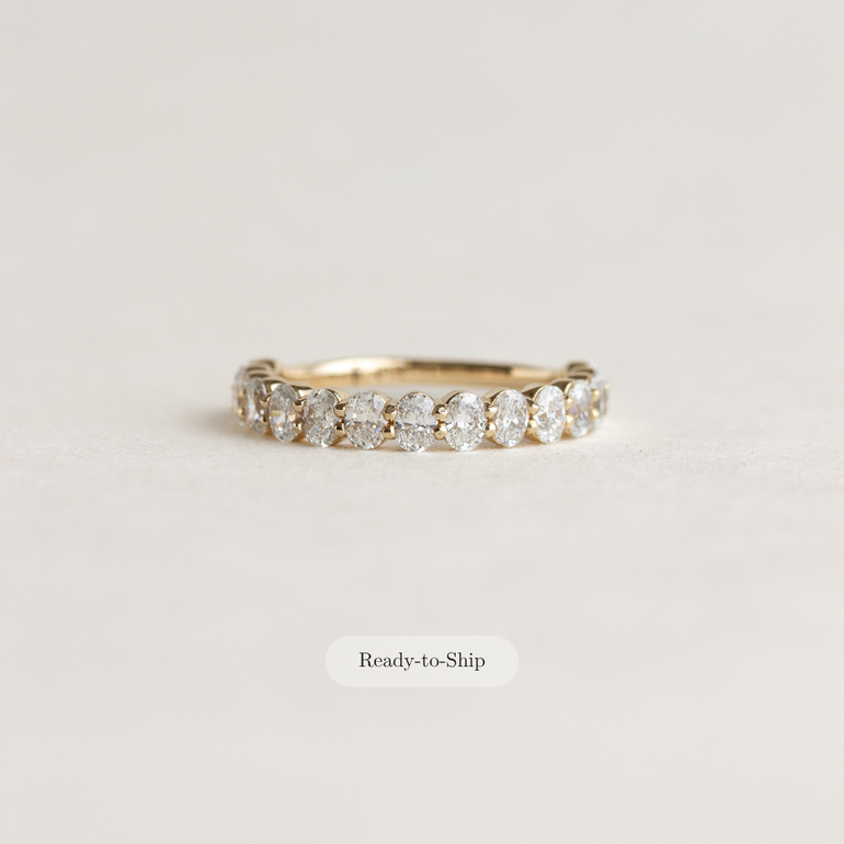 A yellow gold eternity ring with a row of round-cut diamonds, shown on a light beige background with a 'Ready-to-Ship' label below it.