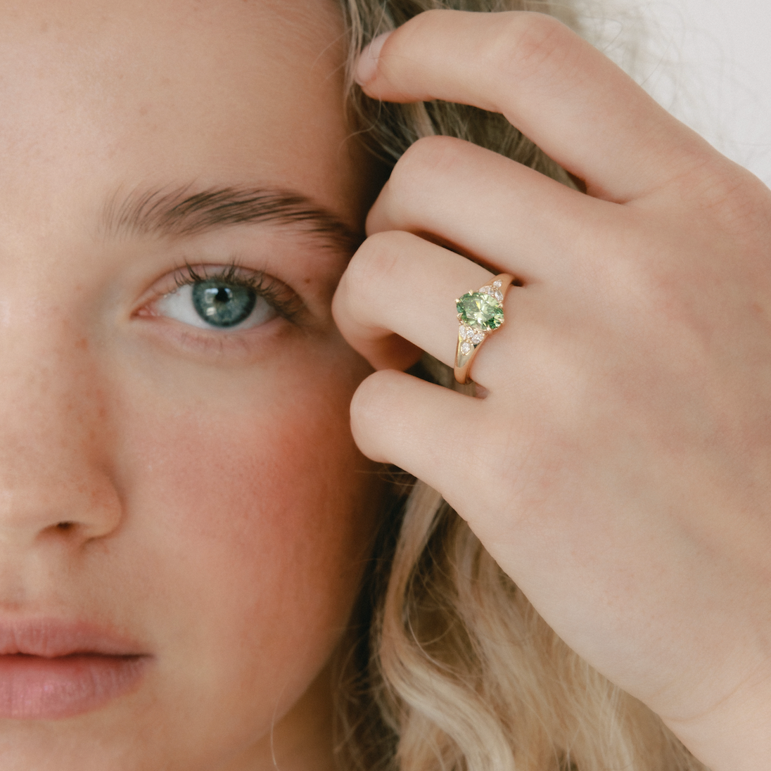 Close-up of a woman wearing a green gemstone ring on her finger.
