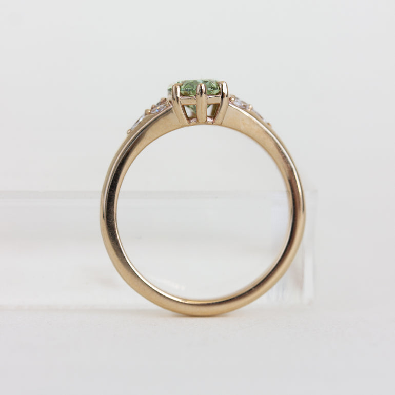 Gold ring with a green gemstone on a white background
