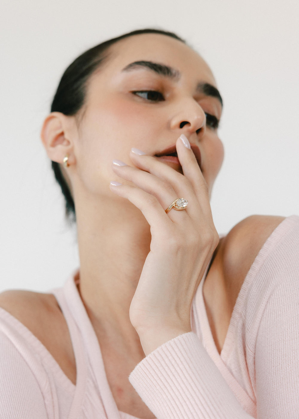Woman wearing a diamond engagement ring on a plain background