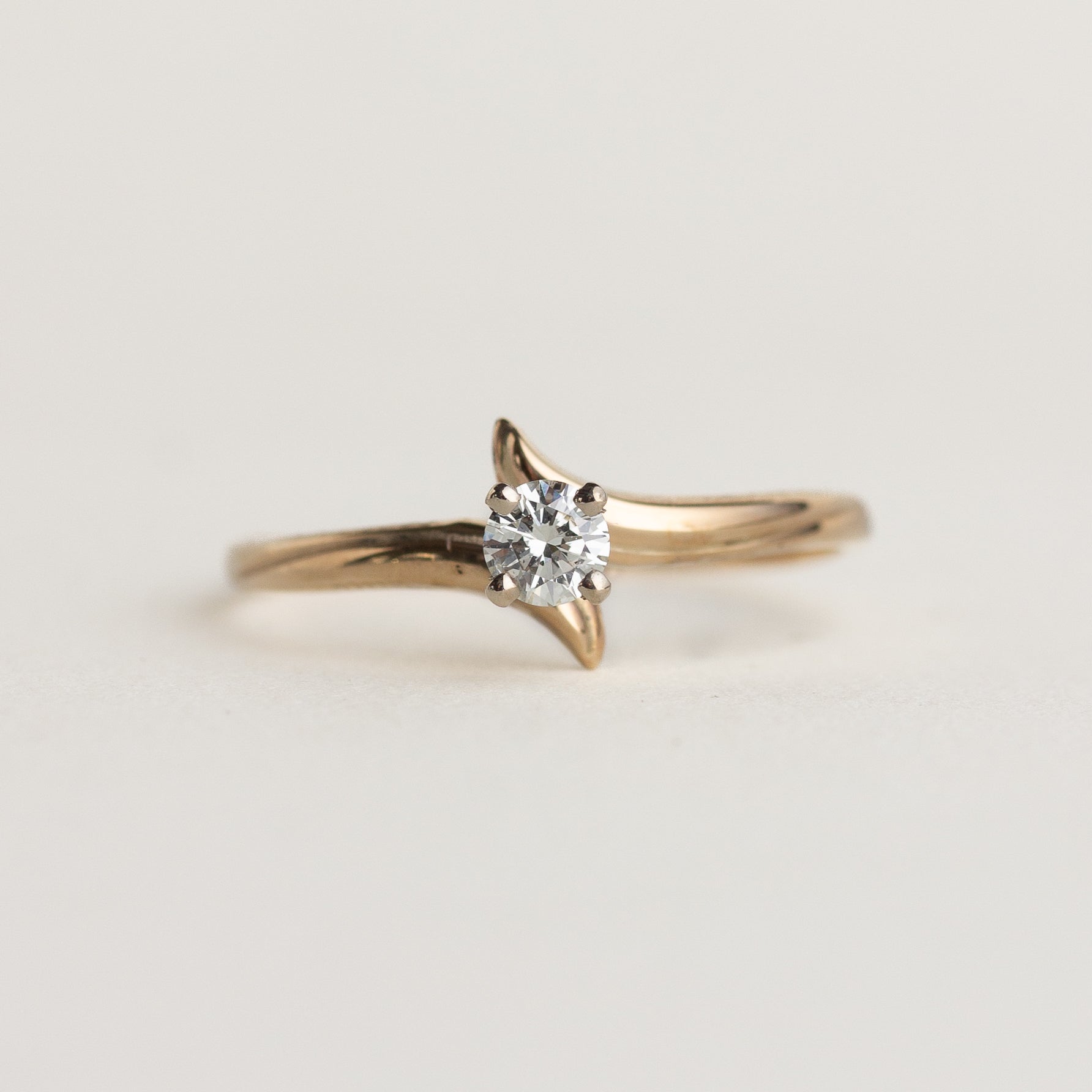 Gold ring with a diamond on a light gray background