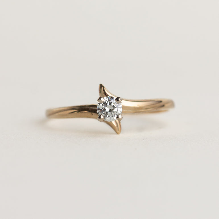 Gold ring with a diamond on a light gray background