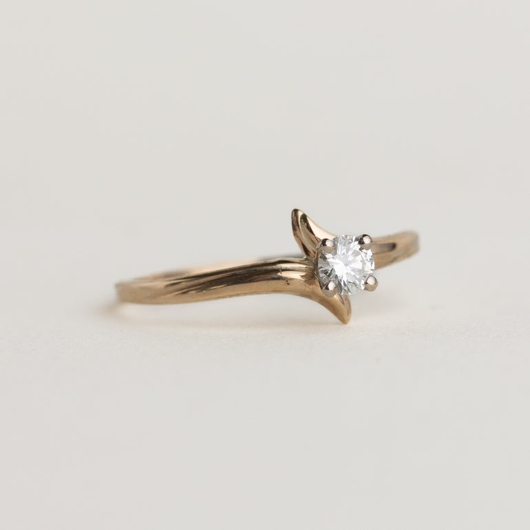 Gold ring with a diamond on a light gray background