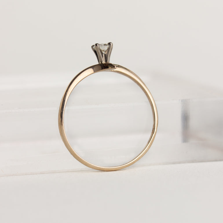 Gold ring with a diamond on a light gray background