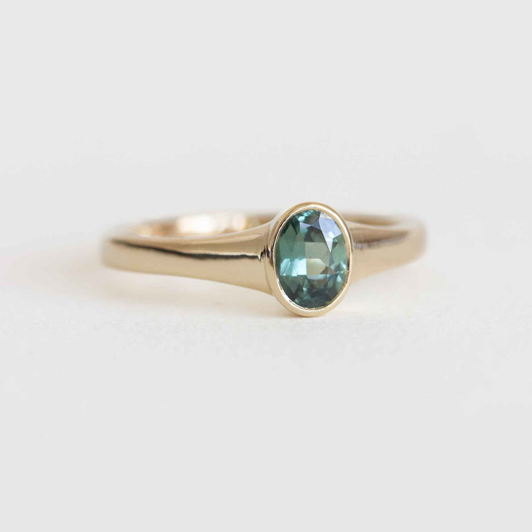 Gold ring with a green gemstone on a light background