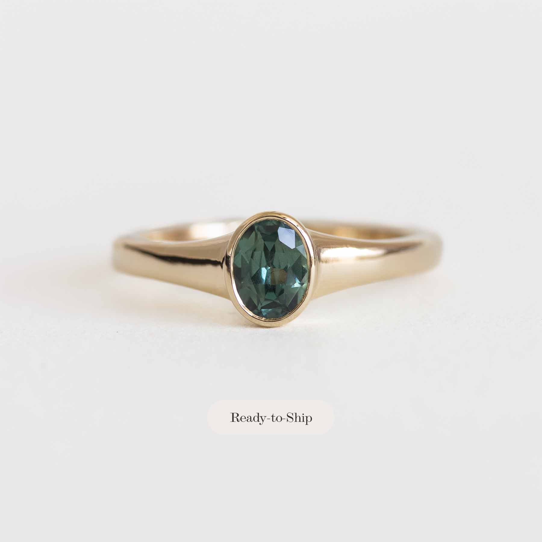 Gold ring with a green gemstone on a white background