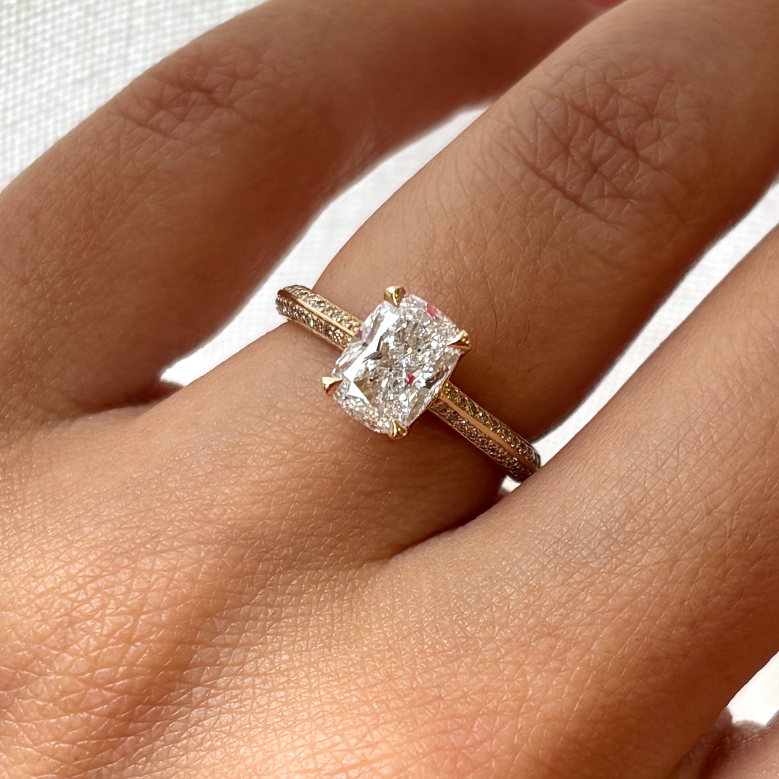 Rose gold ring with a large diamond on a hand against a white background