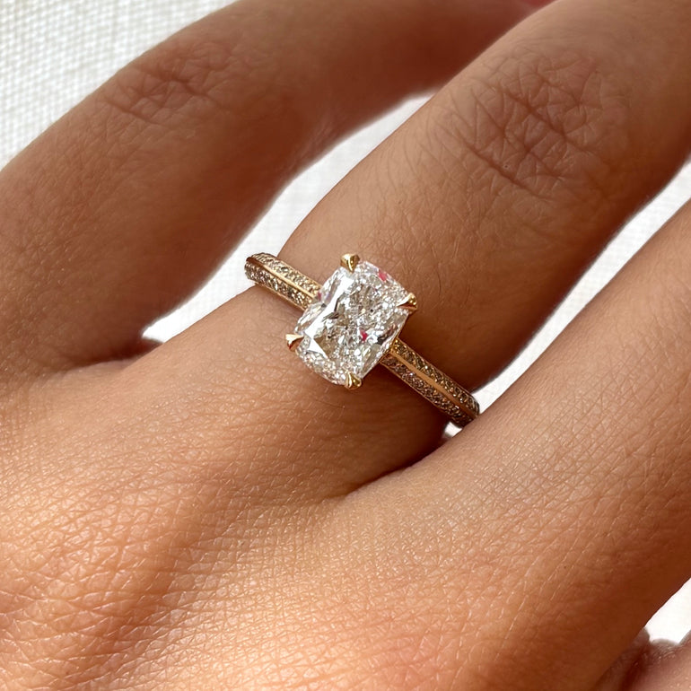 Rose gold ring with a large diamond on a hand against a white background