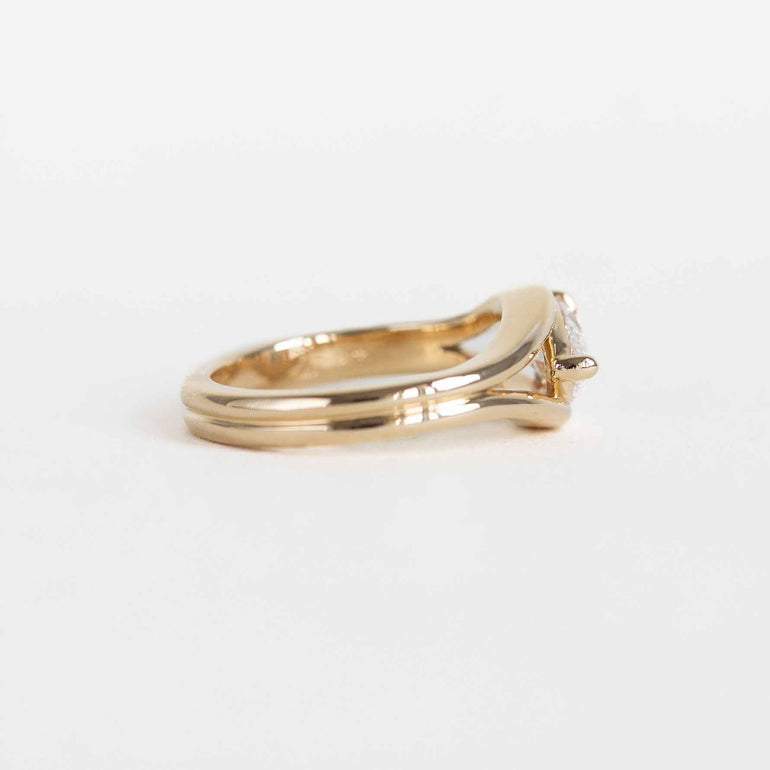 A yellow gold ring featuring a pear-cut lab diamond in a split bypass setting shown on a clean white background.