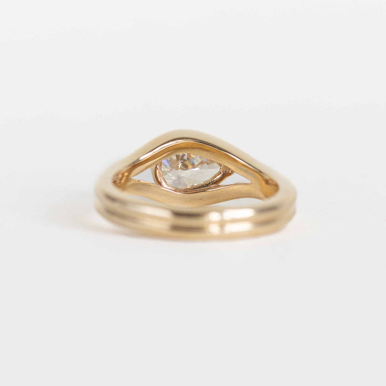 A yellow gold ring featuring a pear-cut lab diamond in a split bypass setting shown on a clean white background.
