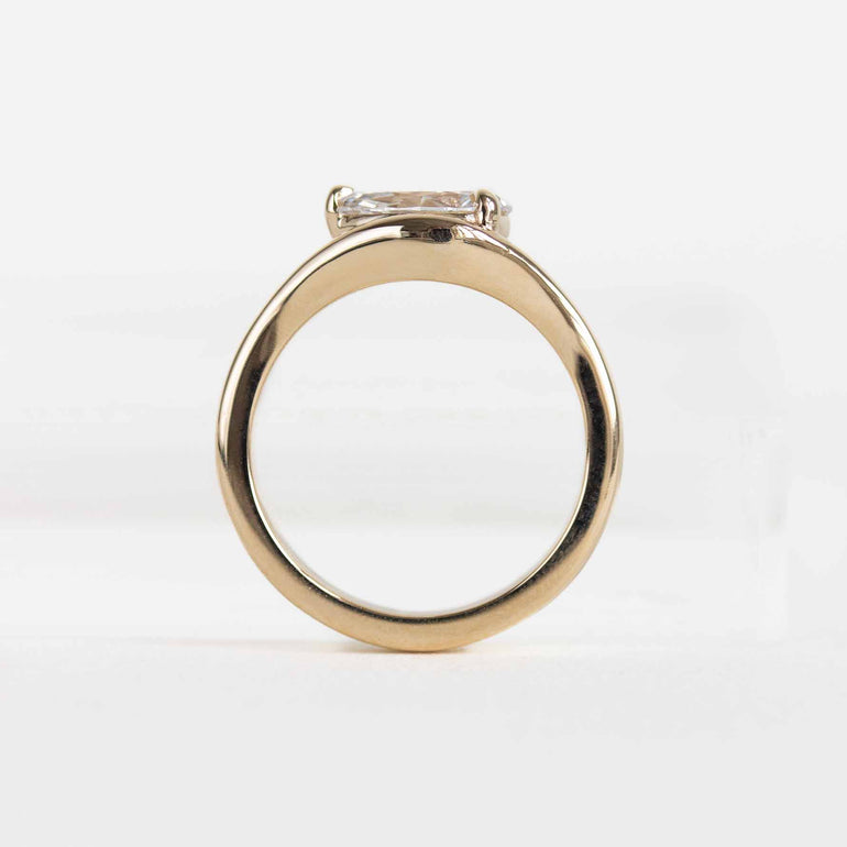 A yellow gold ring featuring a pear-cut lab diamond in a split bypass setting shown on a clean white background.