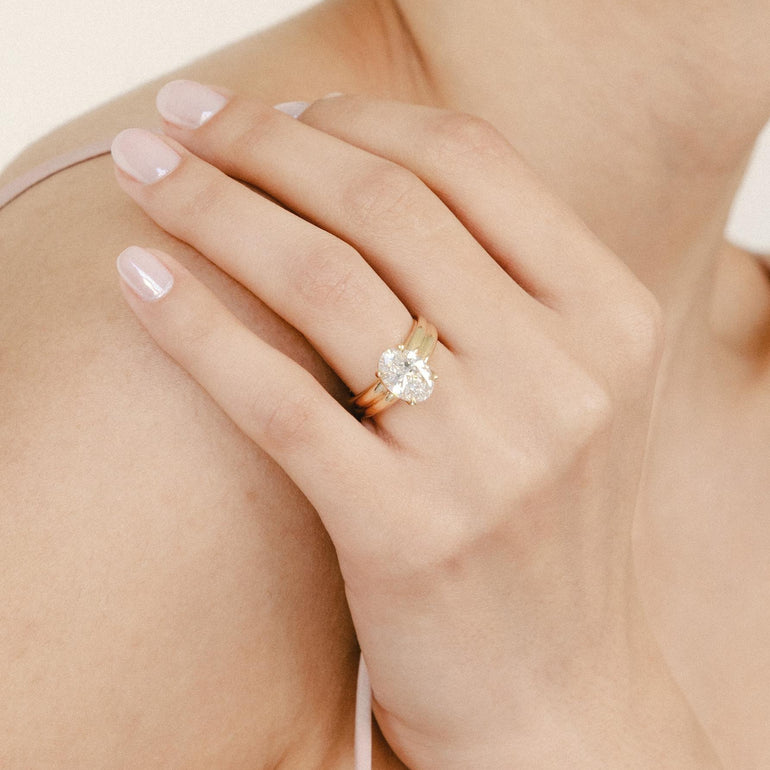 Woman wearing a ring and earring on a plain background