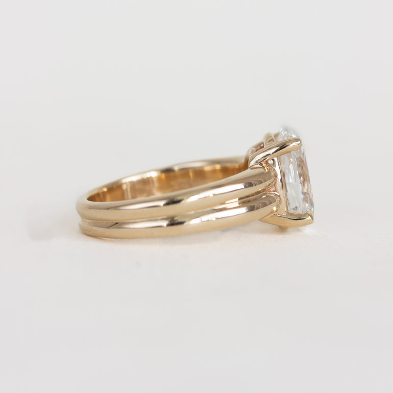 Gold ring with a rectangular diamond on a light gray background
