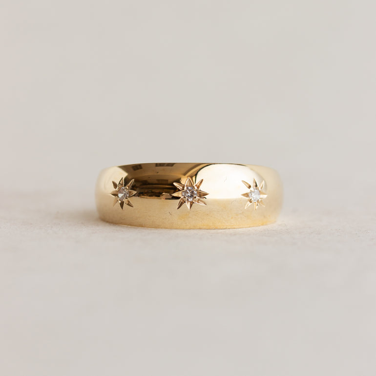 Gold ring with star-shaped diamond cutouts on a light gray background