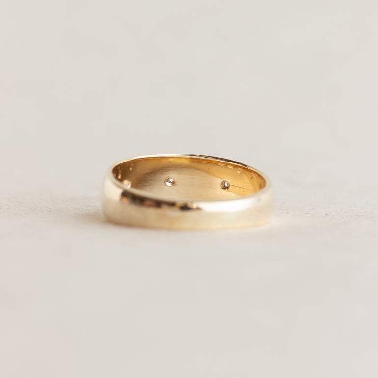 Gold ring with small stones on a light gray background