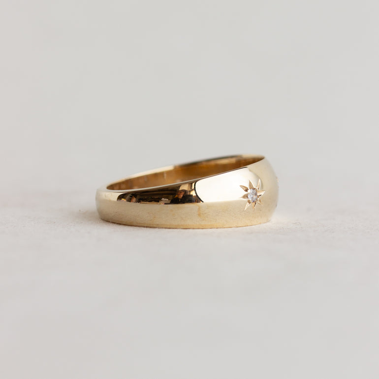 Gold ring with a small diamond on a light gray background