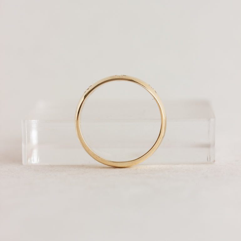Gold ring on a clear stand against a light gray background