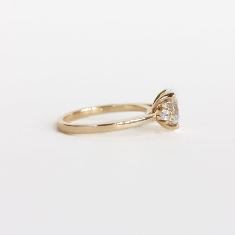 A yellow gold solitaire engagement ring with a lab diamond, shown in a side profile view on a plain white background.
