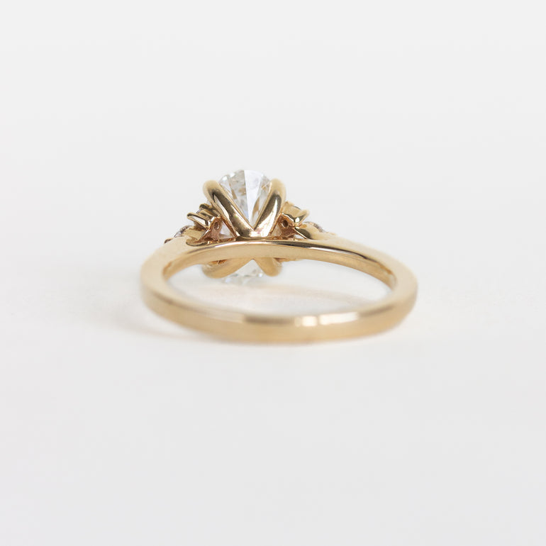 A yellow gold ring with a diamond in a decorative claw setting, photographed on a plain white background.